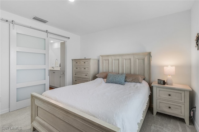 carpeted bedroom featuring ensuite bath and a barn door