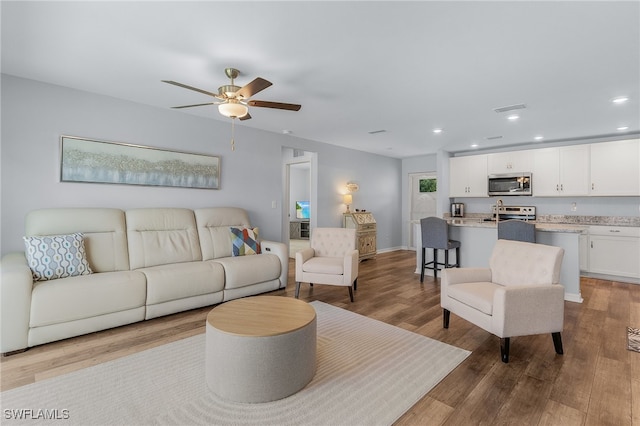 living room featuring light hardwood / wood-style floors and ceiling fan