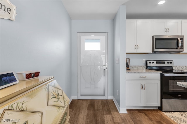 kitchen featuring light stone counters, white cabinets, hardwood / wood-style flooring, and appliances with stainless steel finishes