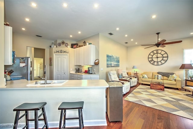 kitchen with a kitchen breakfast bar, white cabinets, kitchen peninsula, ceiling fan, and hardwood / wood-style flooring