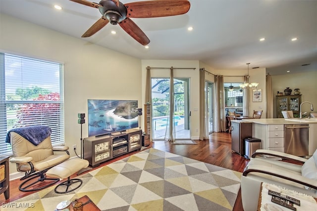 living room featuring sink, ceiling fan with notable chandelier, plenty of natural light, and dark wood-type flooring