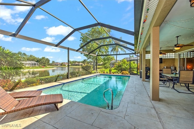 view of swimming pool with a patio, a water view, ceiling fan, and glass enclosure