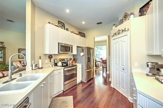 kitchen featuring stainless steel appliances, white cabinets, dark wood-type flooring, and sink