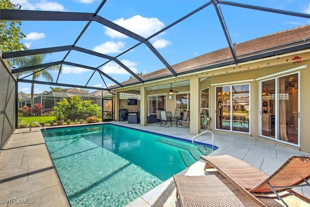 view of swimming pool featuring ceiling fan, a lanai, and a patio