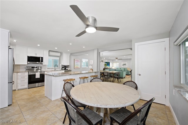 tiled dining space with ceiling fan and sink