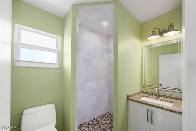 bathroom featuring a tile shower, vanity, and toilet