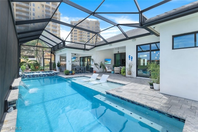 view of swimming pool with glass enclosure, ceiling fan, a pool with connected hot tub, and a patio