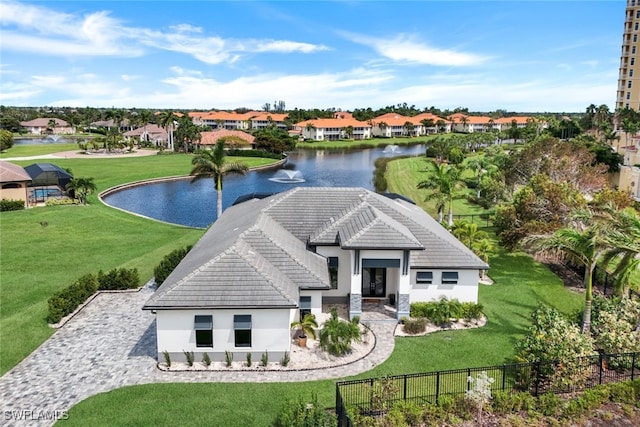 view of front of property with a tile roof, a water view, fence, and a front lawn