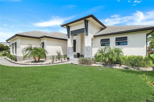 prairie-style home featuring a tile roof, a front lawn, and stucco siding