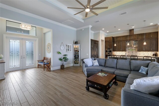 living room featuring french doors, ornamental molding, visible vents, and light wood-style floors