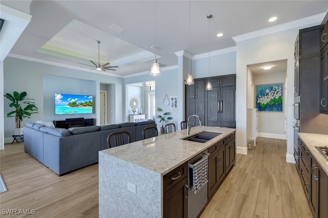 kitchen featuring open floor plan, a kitchen island with sink, light wood-style floors, pendant lighting, and a sink