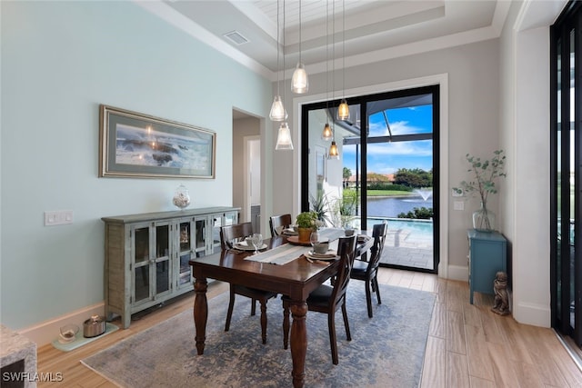 dining area featuring a tray ceiling, visible vents, light wood-style flooring, and baseboards