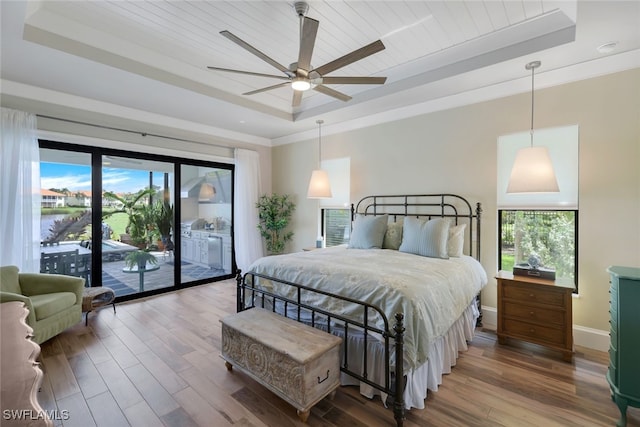 bedroom featuring hardwood / wood-style floors, a raised ceiling, multiple windows, and ceiling fan