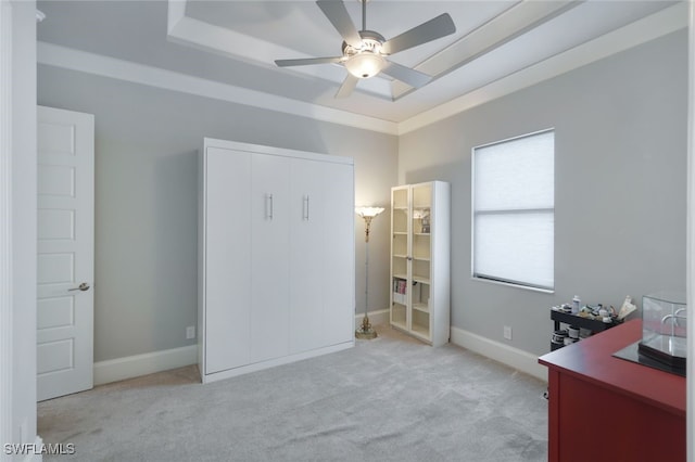 unfurnished office with baseboards, a raised ceiling, a ceiling fan, and light colored carpet