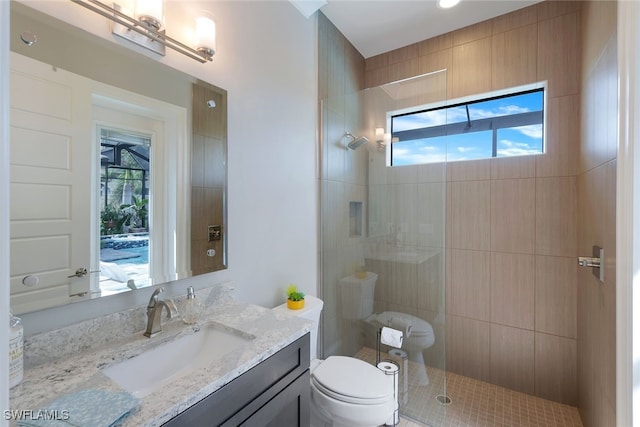 bathroom with a tile shower, vanity, and toilet