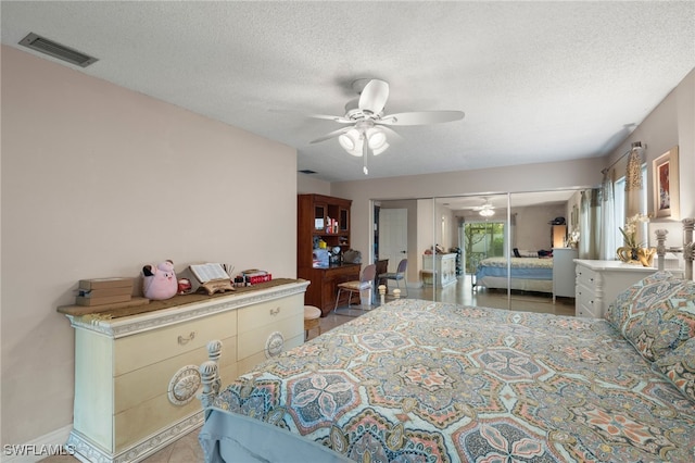 tiled bedroom featuring ceiling fan, a textured ceiling, and a closet