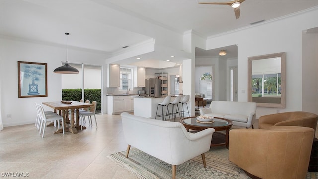 living room with ceiling fan, crown molding, and sink