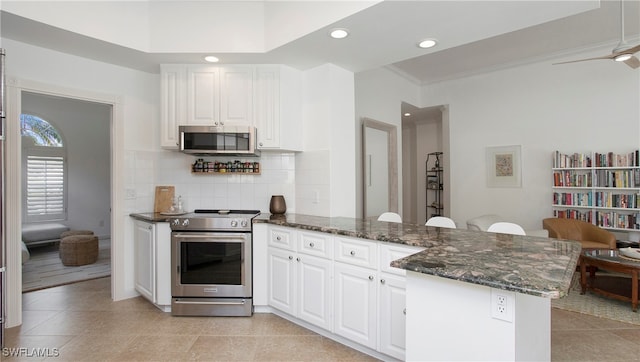 kitchen featuring kitchen peninsula, crown molding, dark stone countertops, white cabinets, and appliances with stainless steel finishes