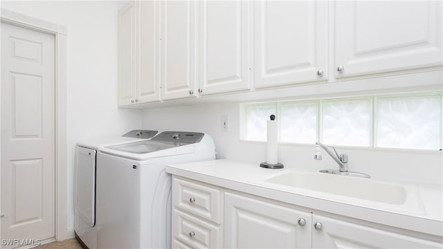 clothes washing area featuring a healthy amount of sunlight, cabinets, independent washer and dryer, and sink