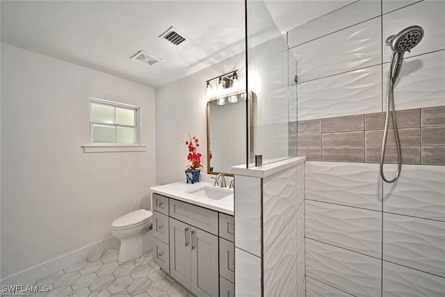 bathroom featuring tile patterned floors, toilet, vanity, and tiled shower