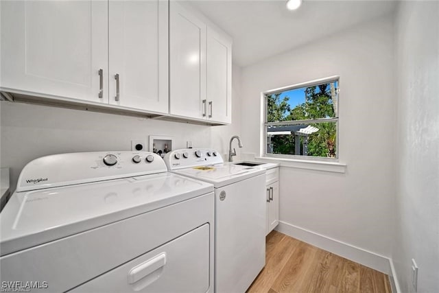 laundry area featuring light hardwood / wood-style floors, washing machine and dryer, sink, and cabinets