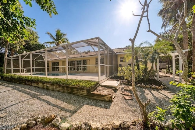 back of property featuring glass enclosure and a patio