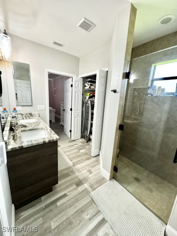 bathroom with walk in shower, wood-type flooring, vanity, and toilet