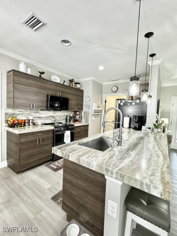 kitchen featuring black range with electric stovetop, a breakfast bar, backsplash, light hardwood / wood-style flooring, and sink