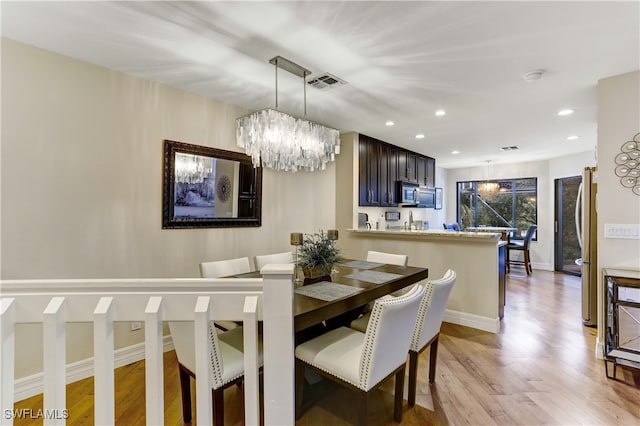 dining area with an inviting chandelier and light wood-type flooring