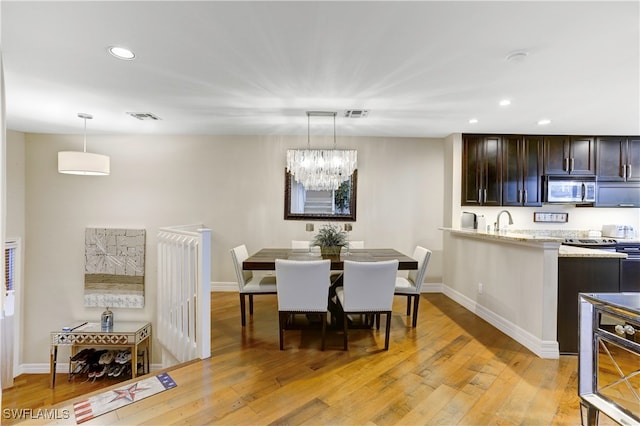 dining space with light hardwood / wood-style flooring and an inviting chandelier