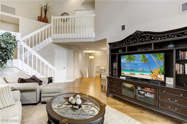 living room with light hardwood / wood-style flooring and a towering ceiling