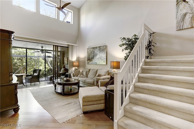 living room with ceiling fan, a high ceiling, and wood-type flooring