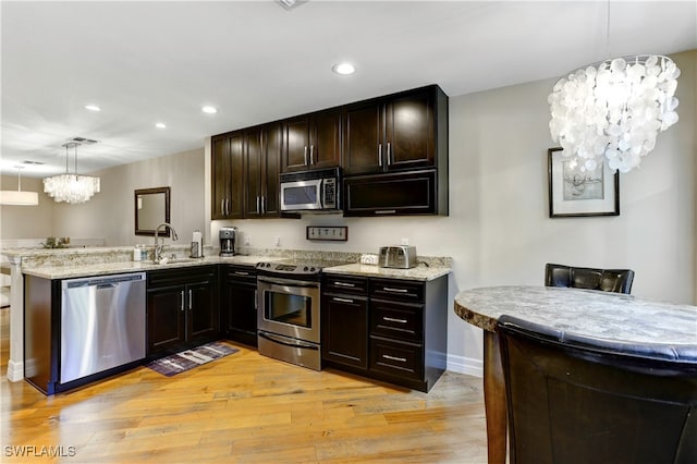 kitchen with kitchen peninsula, stainless steel appliances, light wood-type flooring, decorative light fixtures, and a chandelier