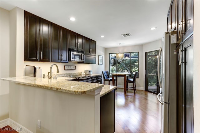 kitchen featuring appliances with stainless steel finishes, light stone counters, kitchen peninsula, wood-type flooring, and sink