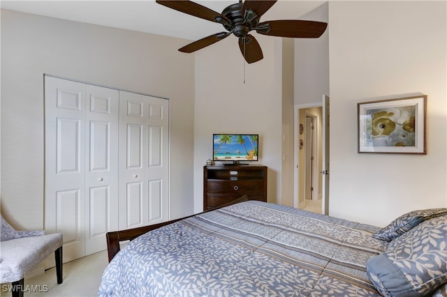 bedroom with a closet, light colored carpet, ceiling fan, and a high ceiling