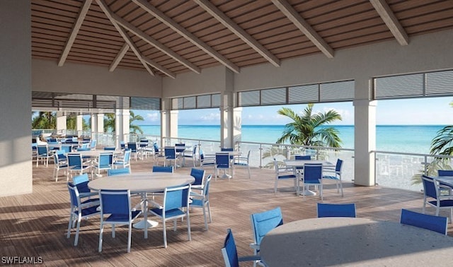 dining area with high vaulted ceiling, a water view, beamed ceiling, and hardwood / wood-style floors