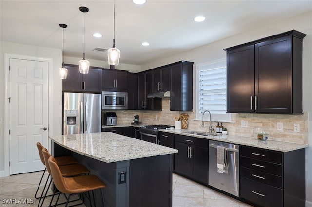 kitchen with a kitchen island, stainless steel appliances, a breakfast bar, sink, and hanging light fixtures