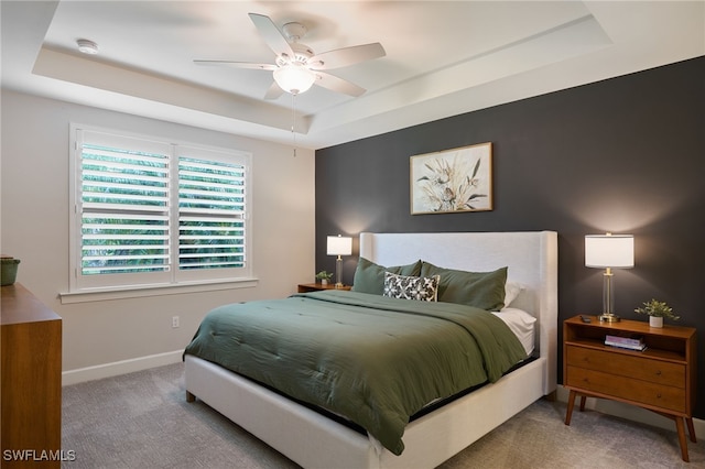 carpeted bedroom featuring a raised ceiling and ceiling fan