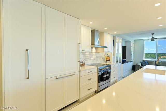 kitchen featuring sink, electric stove, white cabinetry, wall chimney exhaust hood, and ceiling fan