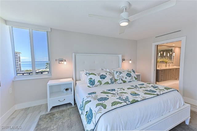 bedroom featuring connected bathroom, hardwood / wood-style floors, and ceiling fan