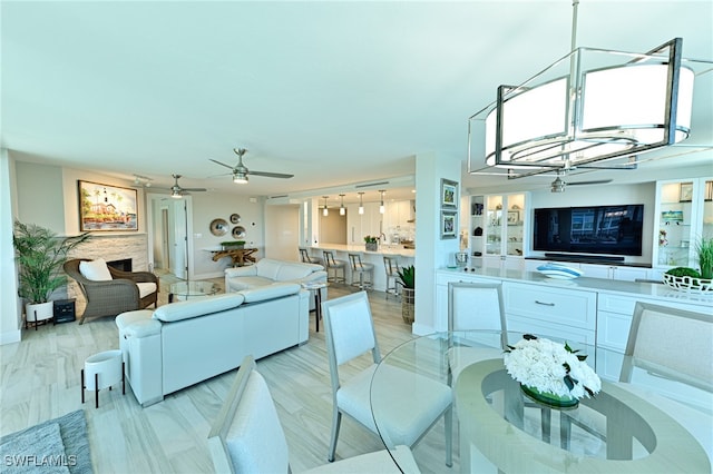 dining area featuring ceiling fan with notable chandelier and a stone fireplace