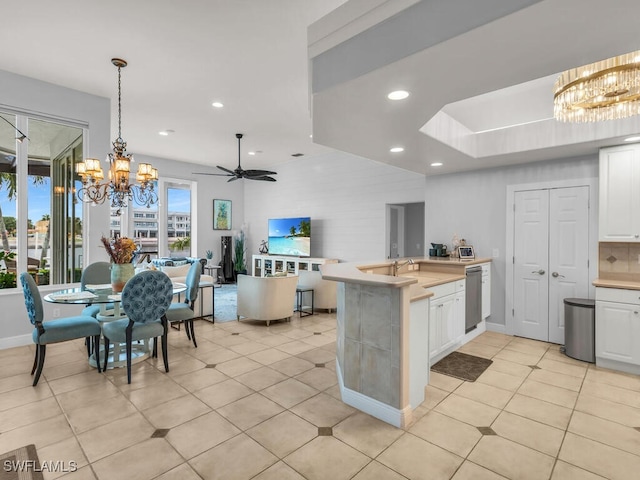 kitchen featuring white cabinets, hanging light fixtures, sink, dishwasher, and ceiling fan with notable chandelier