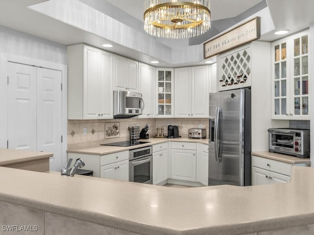 kitchen featuring white cabinets, hanging light fixtures, an inviting chandelier, decorative backsplash, and appliances with stainless steel finishes