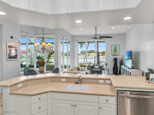 kitchen with ceiling fan with notable chandelier, white cabinets, dishwasher, and sink