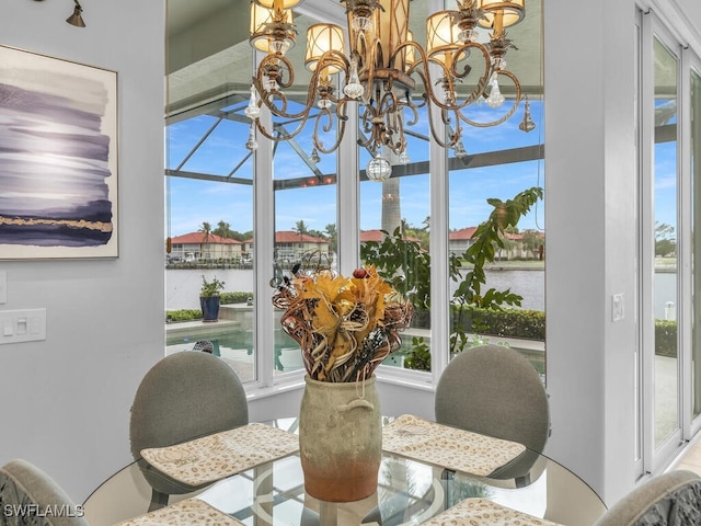 dining area featuring a water view and an inviting chandelier