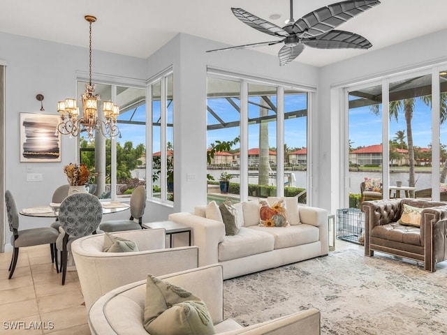 tiled living room featuring ceiling fan with notable chandelier, plenty of natural light, and a water view