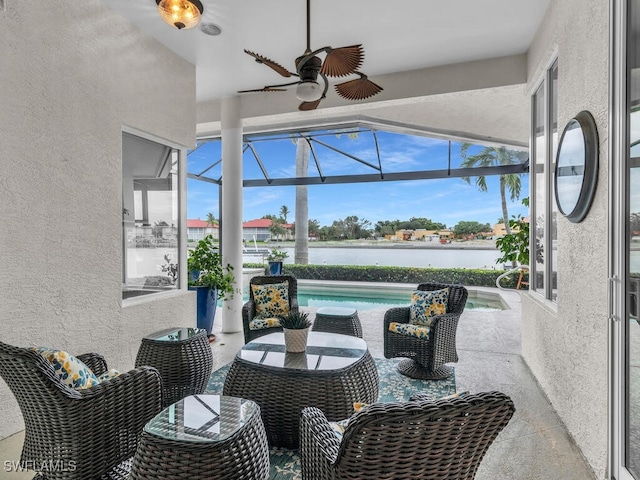 sunroom with ceiling fan and a water view