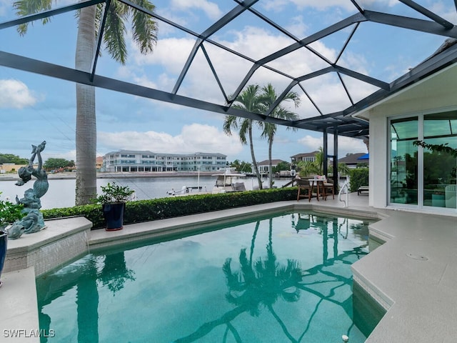 view of pool featuring glass enclosure, a water view, and a patio area