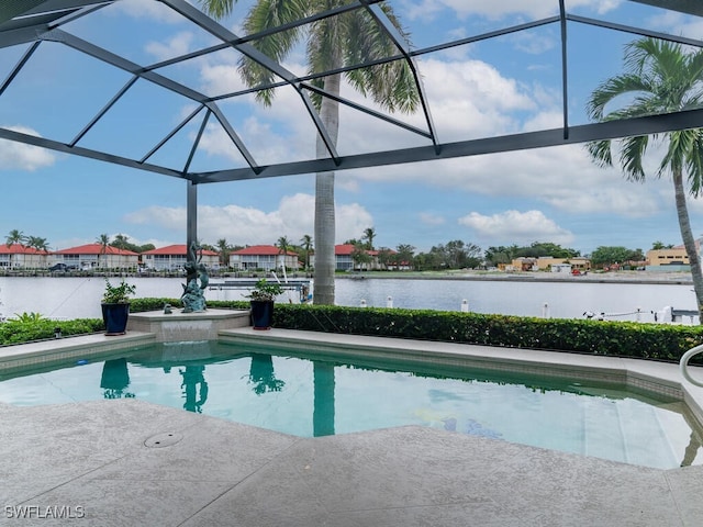 view of pool featuring glass enclosure, a water view, and a patio area