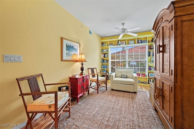 sitting room with ceiling fan and carpet